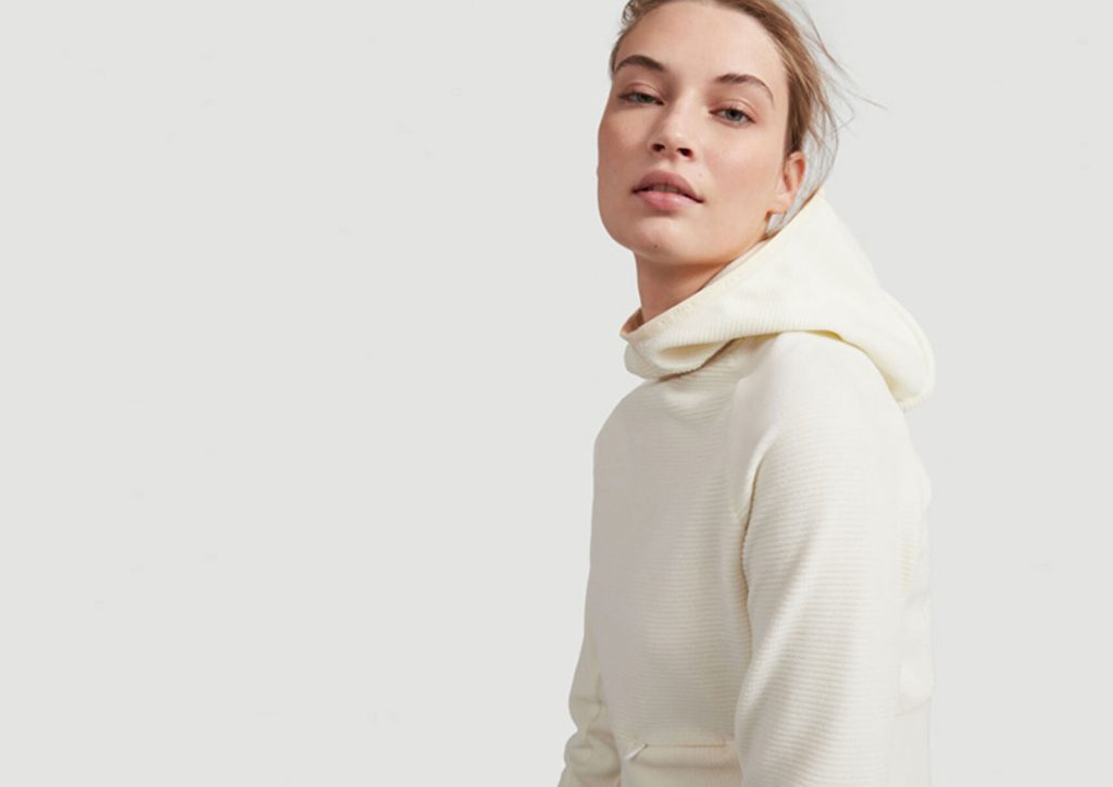 A woman wearing a off white ribbed jersey hooded sweatshirt
