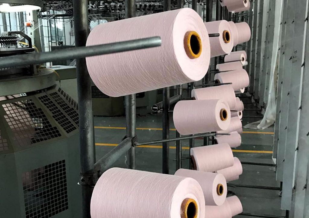 Pink yarns on a round knit machine in a clothing factory in Pakistan